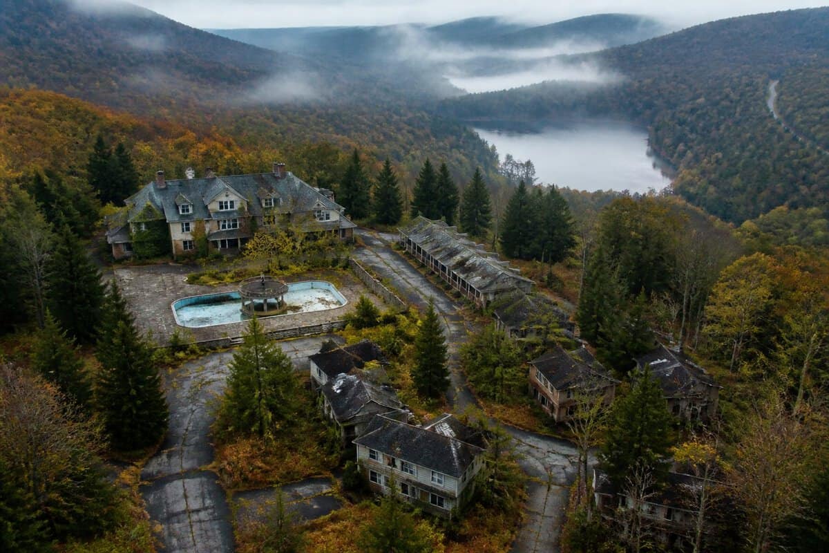 An abandoned honeymoon resort surrounded by forests, winding roads, and misty mountains in the Pocono region.