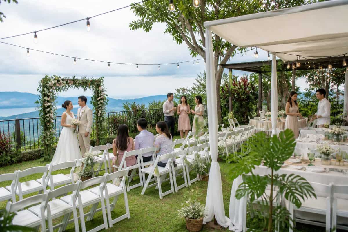 An intimate garden wedding ceremony in Tagaytay with simple floral decorations, seated guests, and scenic hills in the background.