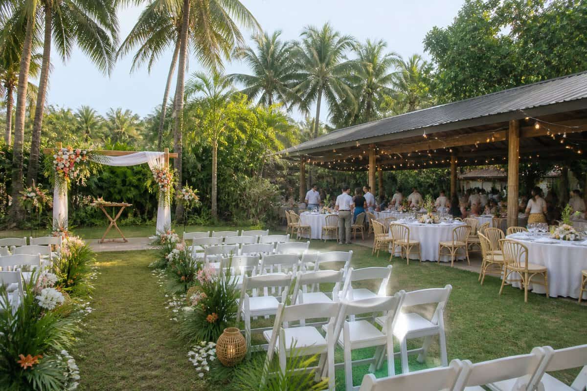 A simple garden wedding ceremony and reception setup surrounded by tropical greenery.