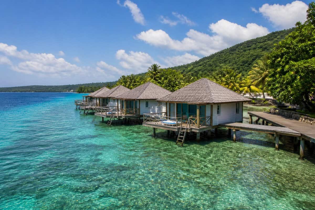 Overwater bungalows on a wooden pier above clear turquoise water in Jamaica.