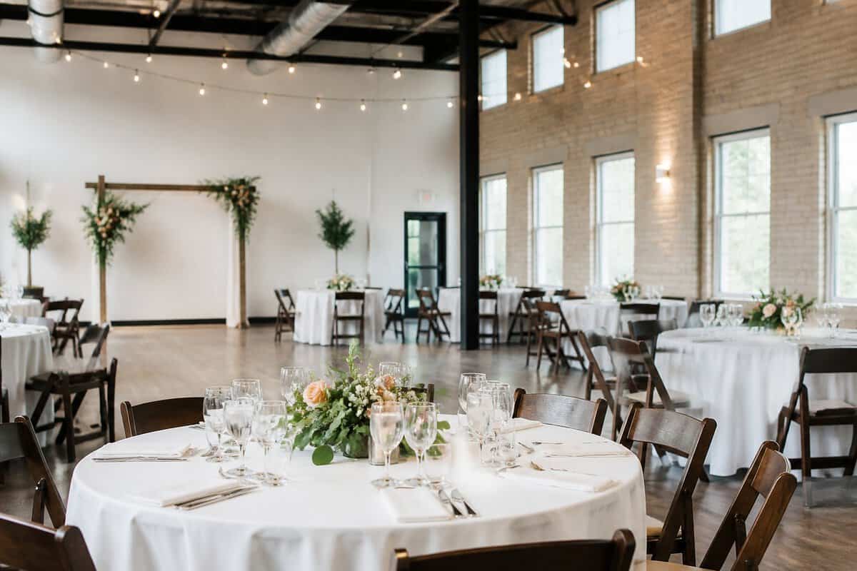 An affordable wedding venue is arranged with simple decorated tables and a modest ceremony arch.