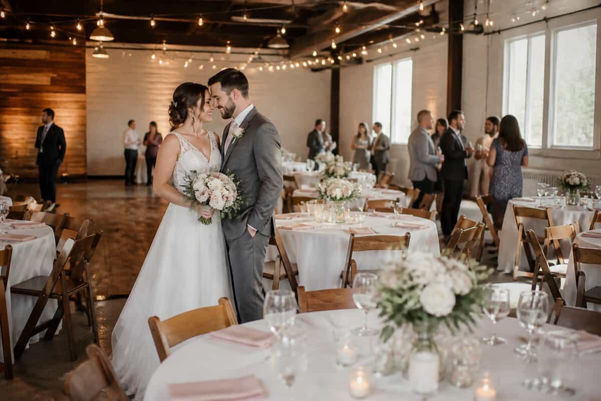 A newlywed couple celebrates at an affordable wedding reception in a warmly decorated venue.