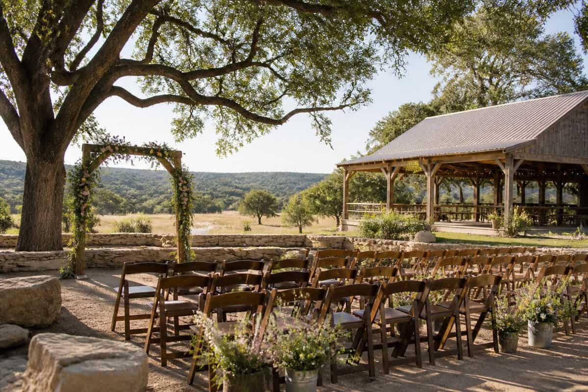 An affordable outdoor wedding venue with wooden chairs, a floral arch, and a rustic pavilion in the Texas Hill Country.