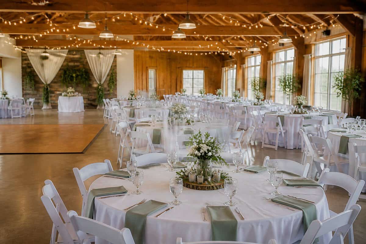 A bright, affordable wedding reception venue with tables, simple floral centerpieces, and seating for a large group.