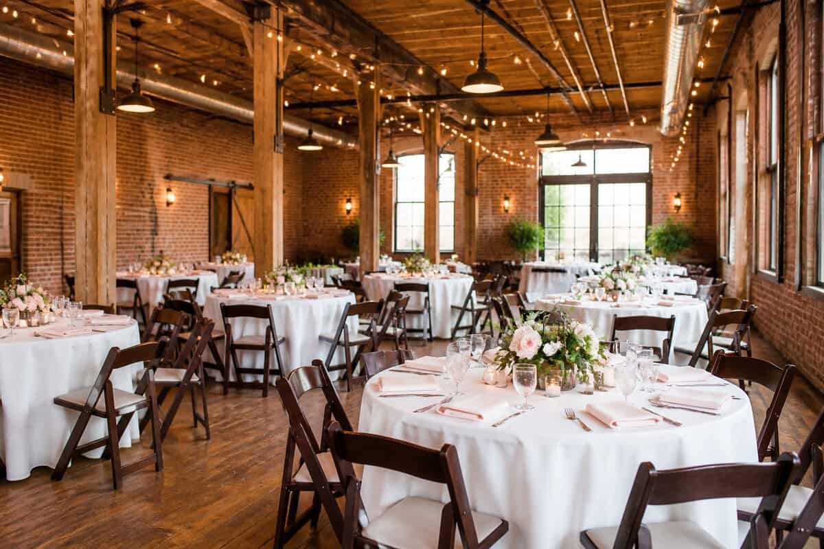 An affordable-looking wedding reception venue in Fort Worth with simple decorated tables and warm lighting.