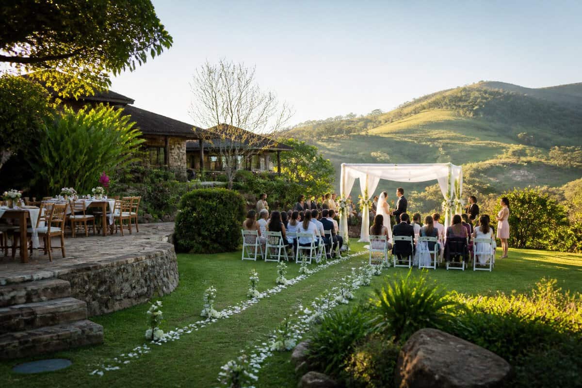 An intimate outdoor wedding ceremony at a modest countryside venue surrounded by lush greenery and rolling hills.