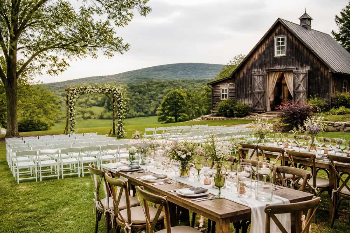 A simple outdoor wedding setup beside a rustic venue with green Hudson Valley hills in the background.