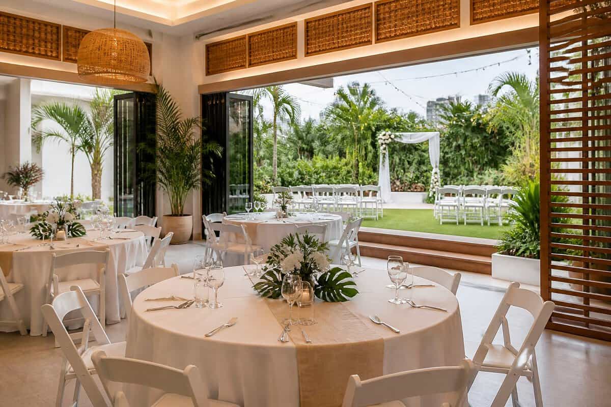 An elegant, modest wedding venue with a decorated reception hall opening onto a tropical garden.