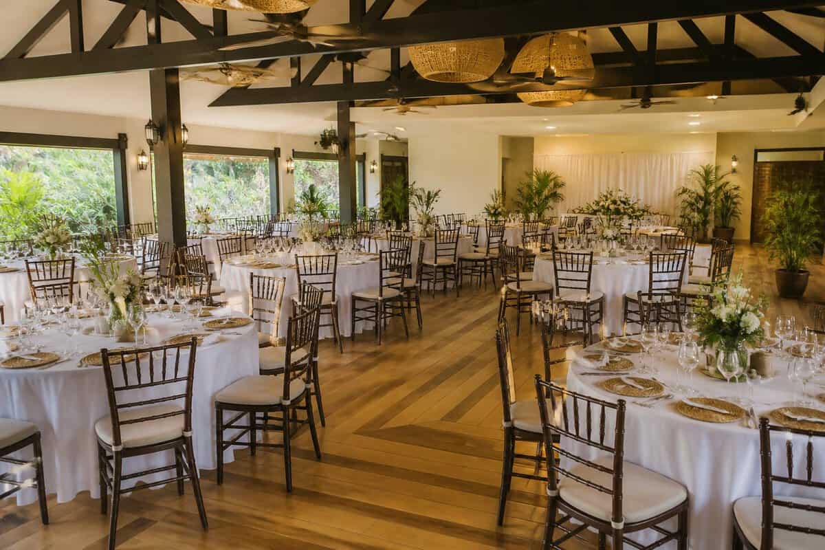 A bright wedding reception hall in Manila with neatly arranged tables, chairs, floral centerpieces, and ample space for guests.