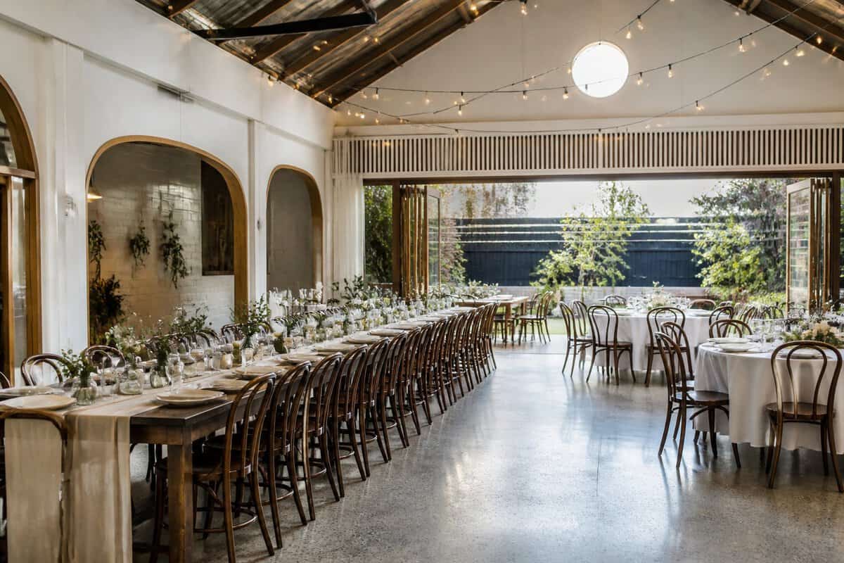 A welcoming wedding venue with simple decorations, flexible seating, and greenery.