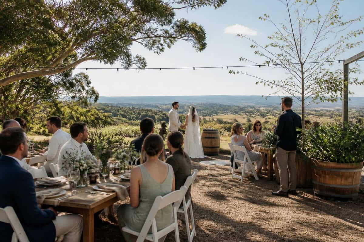 An intimate outdoor wedding reception at a welcoming venue with simple elegant decorations and guests gathered nearby.