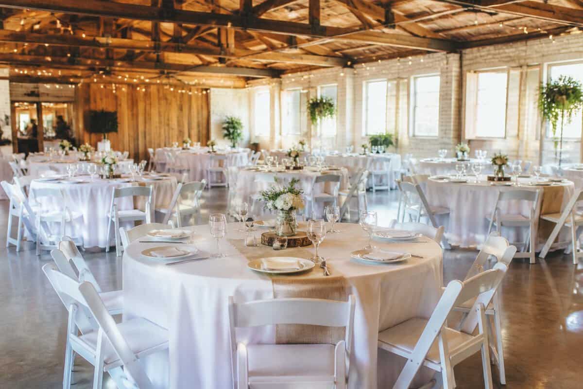 A welcoming wedding reception setup in an affordable event venue with simple floral centerpieces and warm string lights.