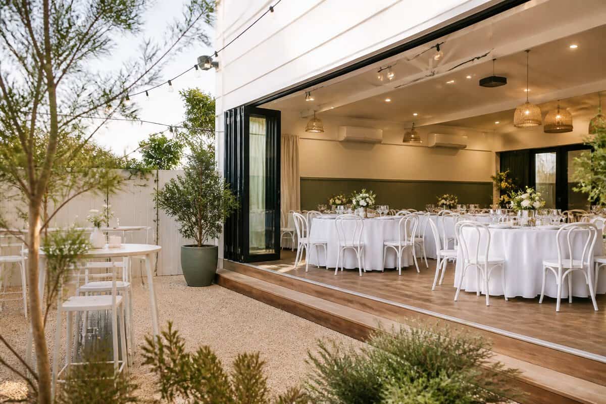 An inviting wedding venue with simply decorated tables opening onto a sunny courtyard.