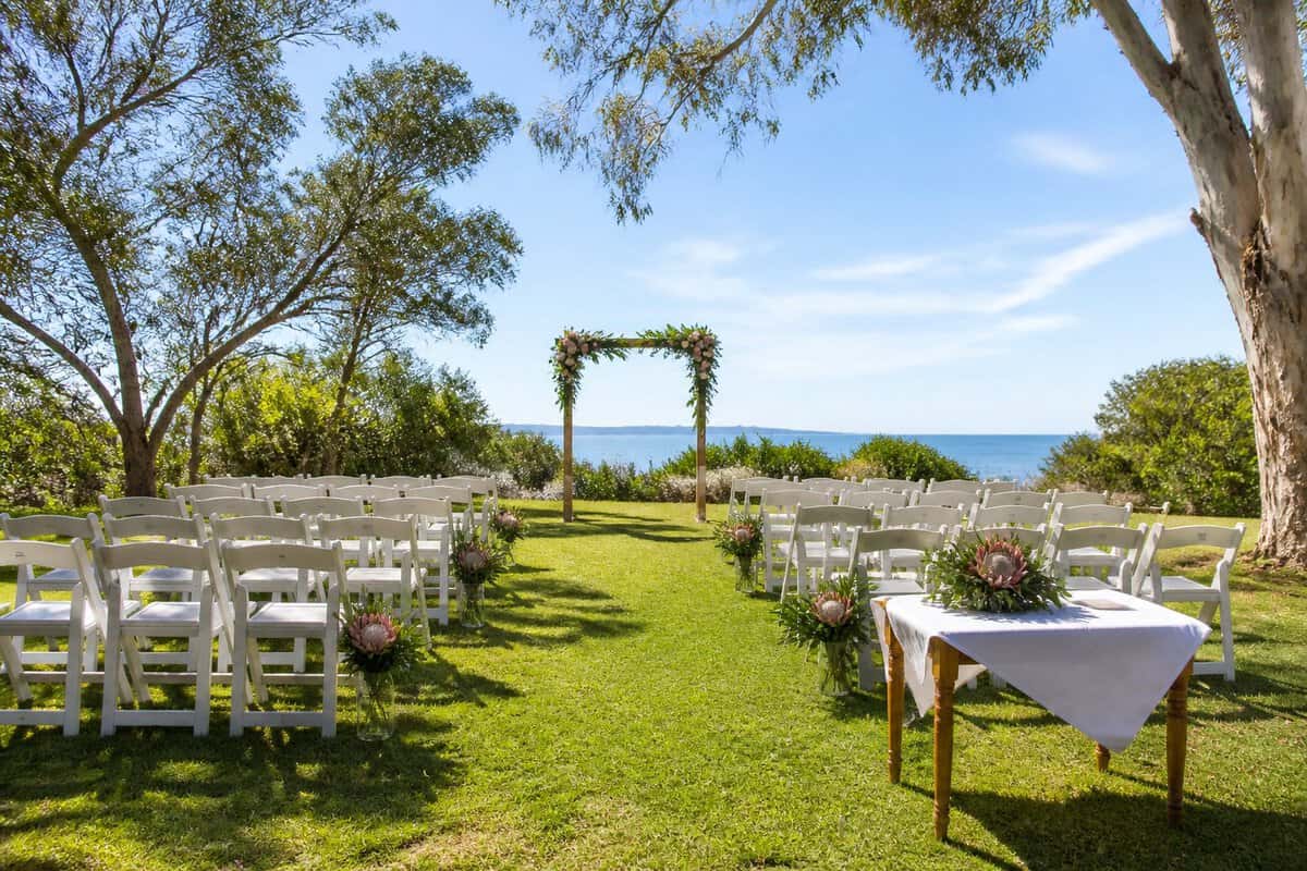 A simple outdoor wedding setup at a landscaped Queensland venue with chairs, flowers, and tropical greenery.