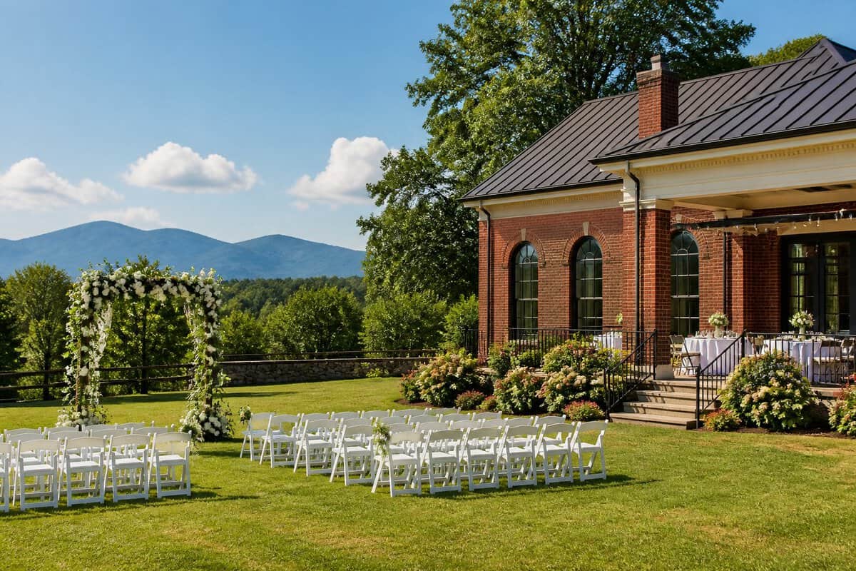 A charming wedding venue with simple outdoor ceremony seating, floral decorations, landscaped grounds, and distant Blue Ridge Mountains.