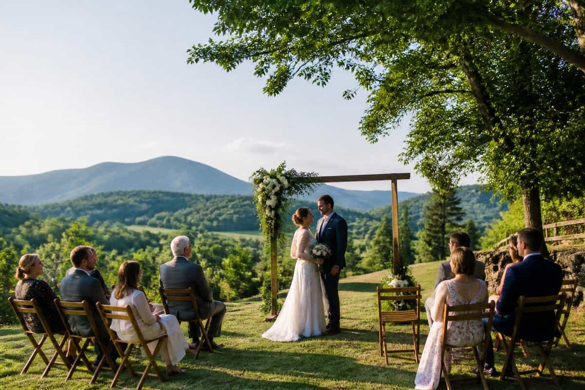 A small wedding ceremony taking place outdoors at a scenic mountain venue with a couple and a few guests.