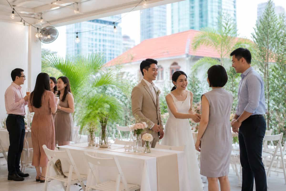 A newlywed couple celebrates with guests at an intimate decorated wedding venue surrounded by greenery.