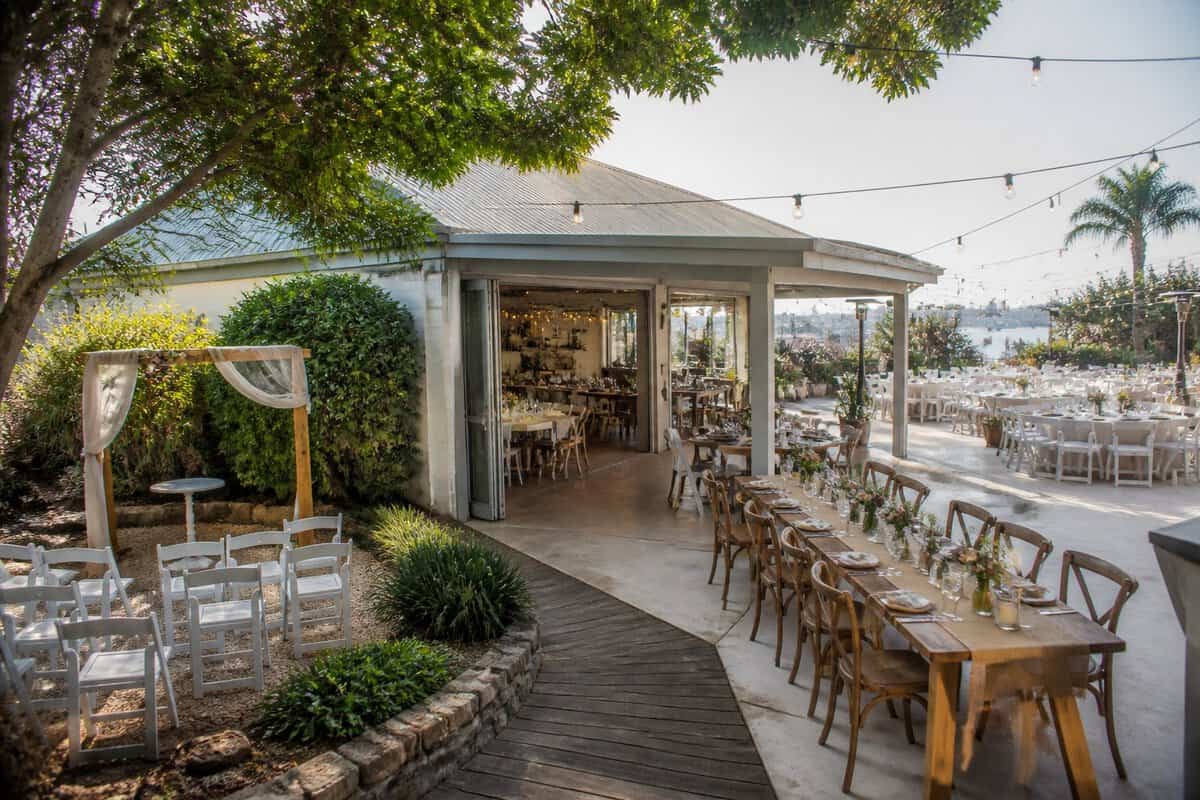A welcoming outdoor wedding venue with garden seating, decorated tables, and string lights.
