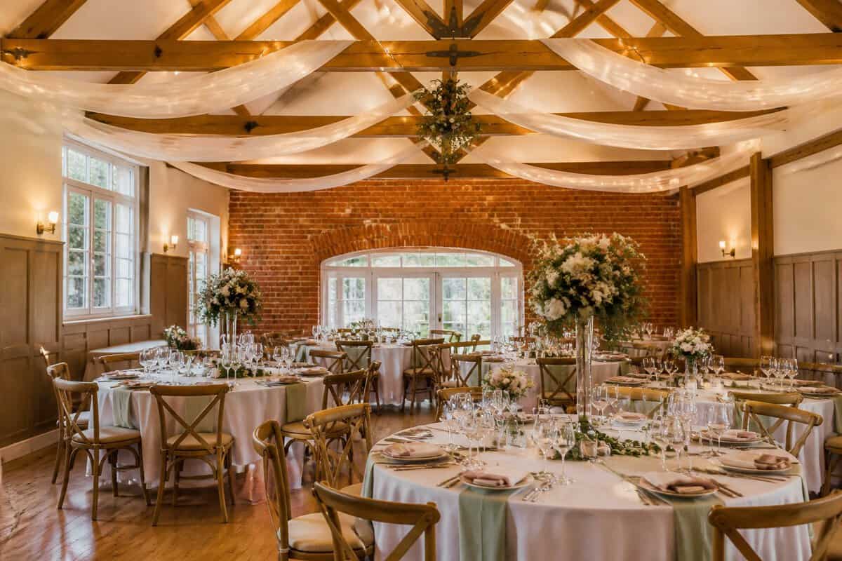 A warmly decorated wedding reception room with tables, chairs, and simple floral centerpieces.