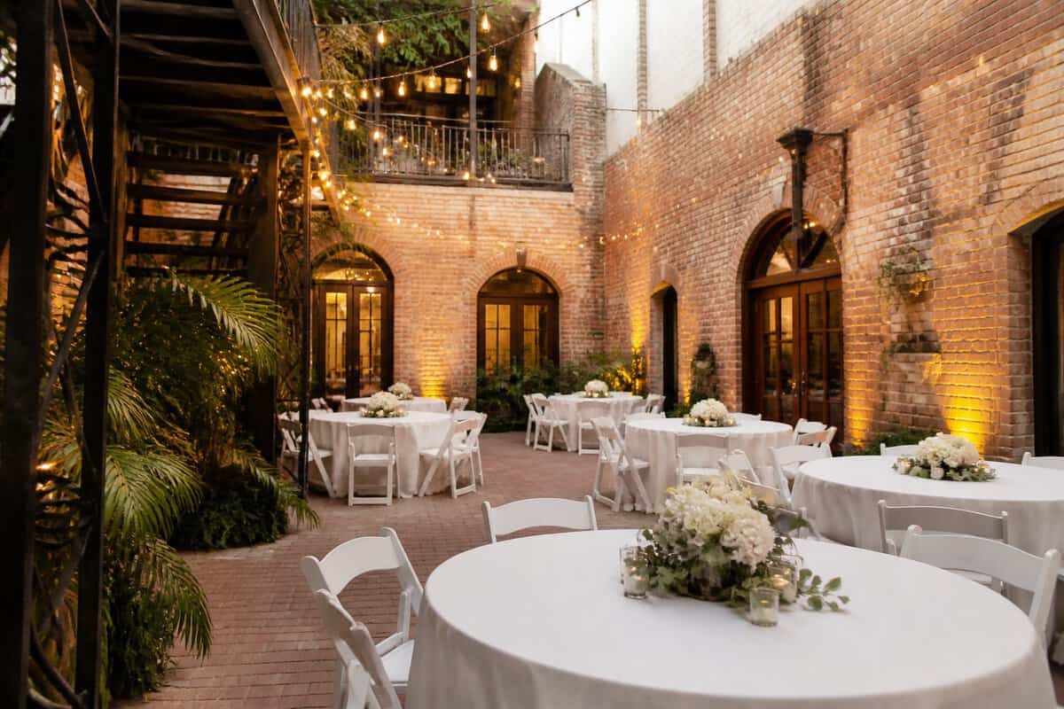 An intimate wedding venue with brick walls, string lights, and simply decorated tables.