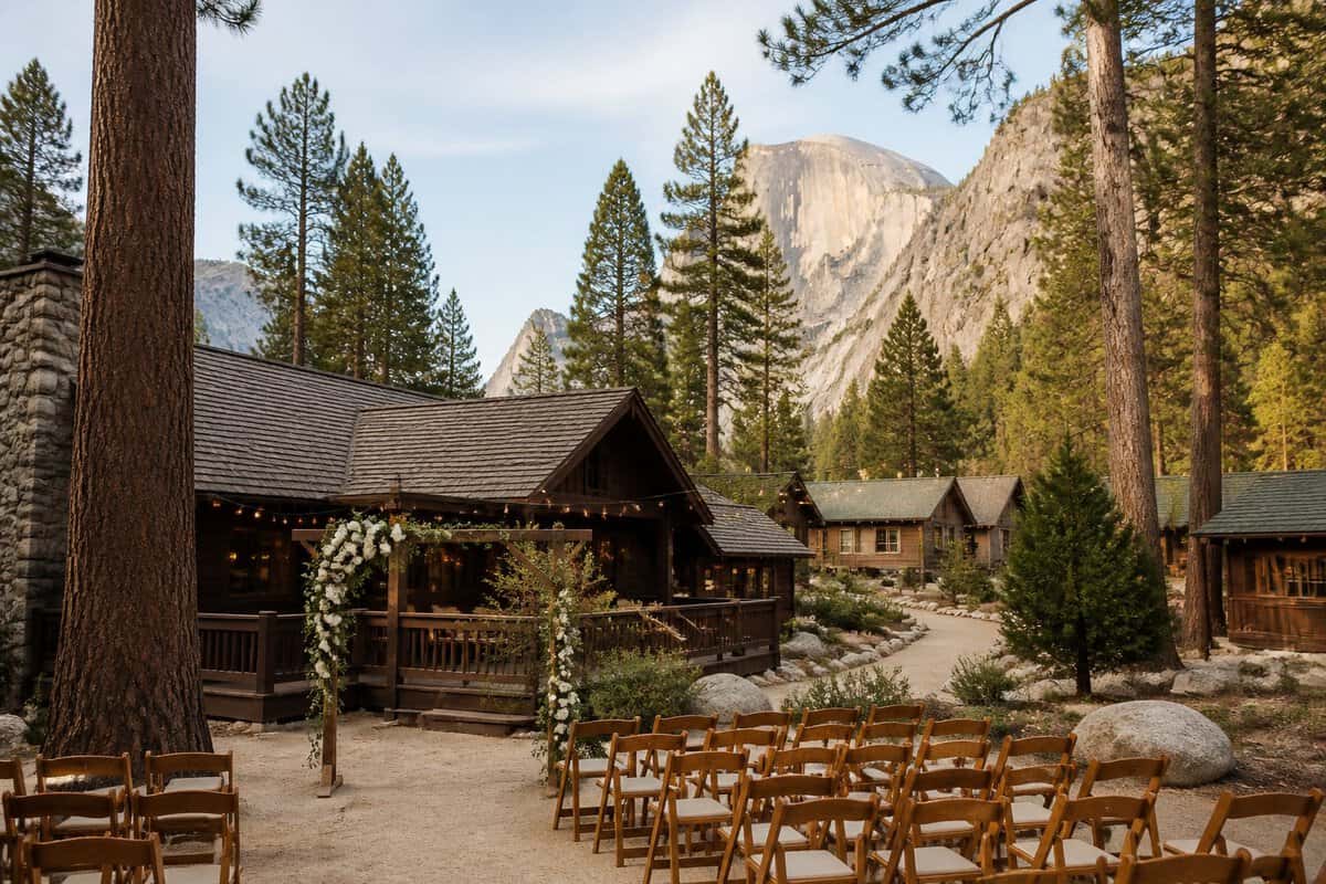 Rustic cabins and a small outdoor wedding arbor surrounded by pine trees near Yosemite's granite mountains.