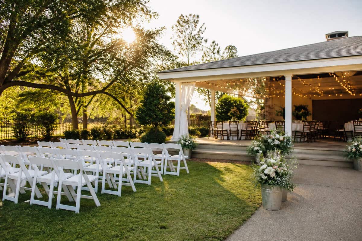 An inviting outdoor wedding ceremony setup at a modest venue surrounded by trees and greenery.