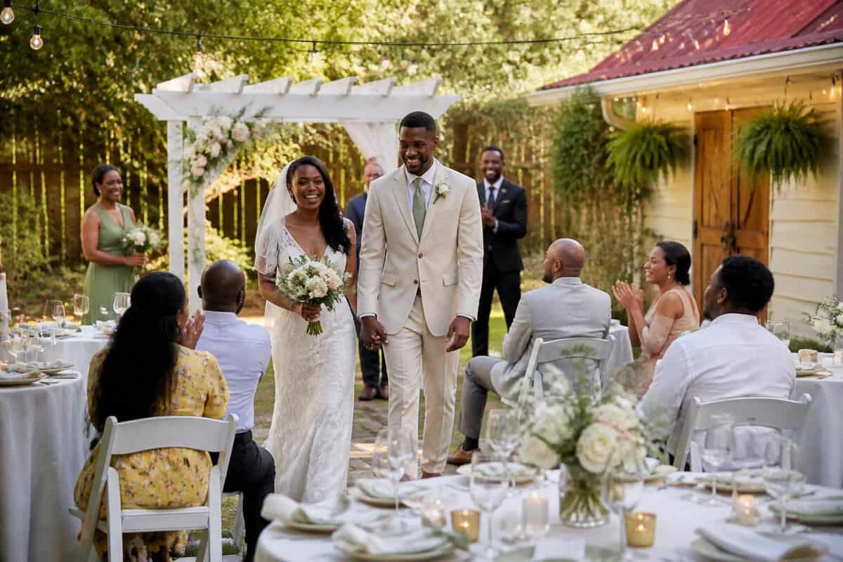 A couple and guests celebrate at an intimate outdoor wedding venue with simple elegant decorations.