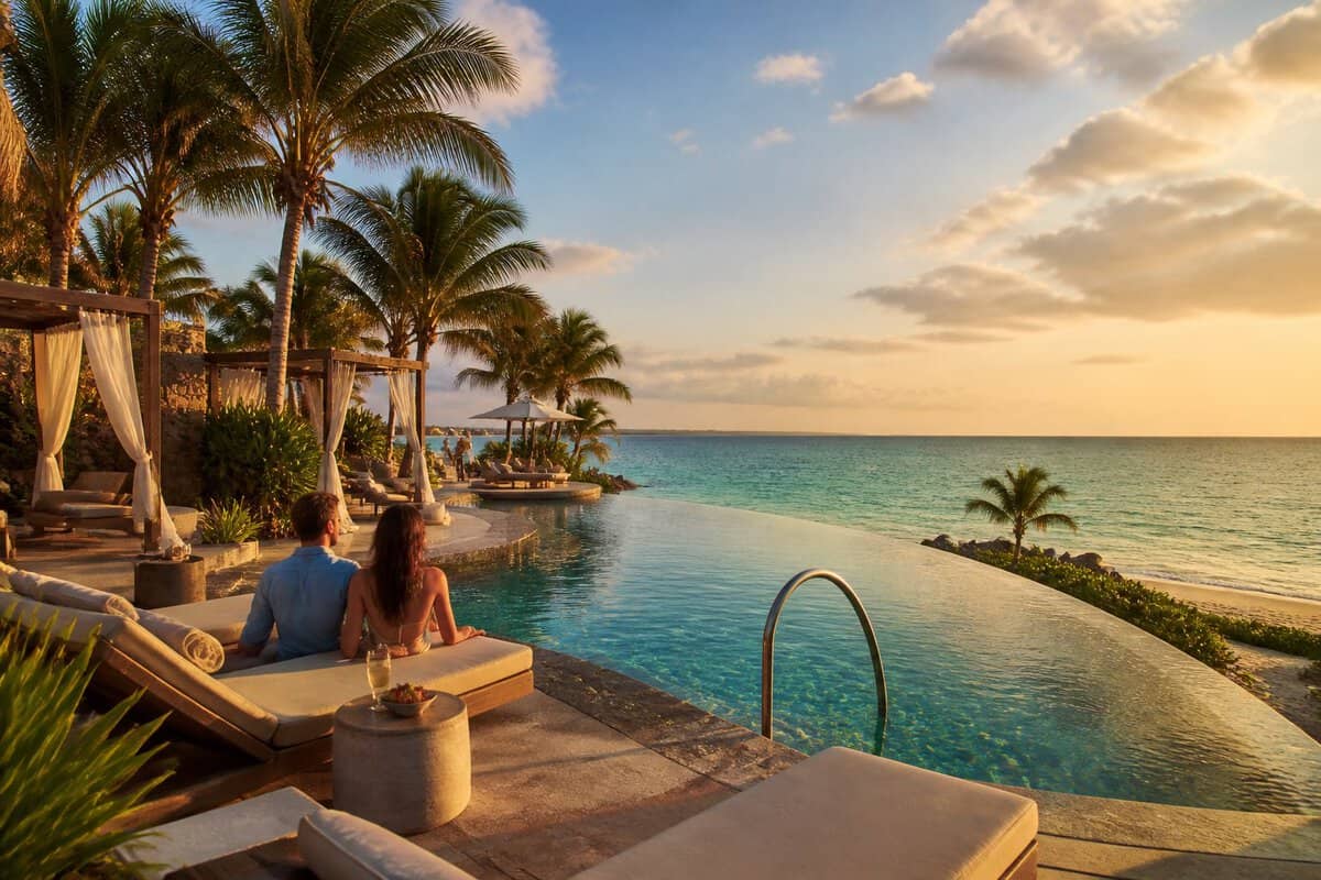 Adults relax beside an infinity pool at a luxurious Mexican beachfront resort.