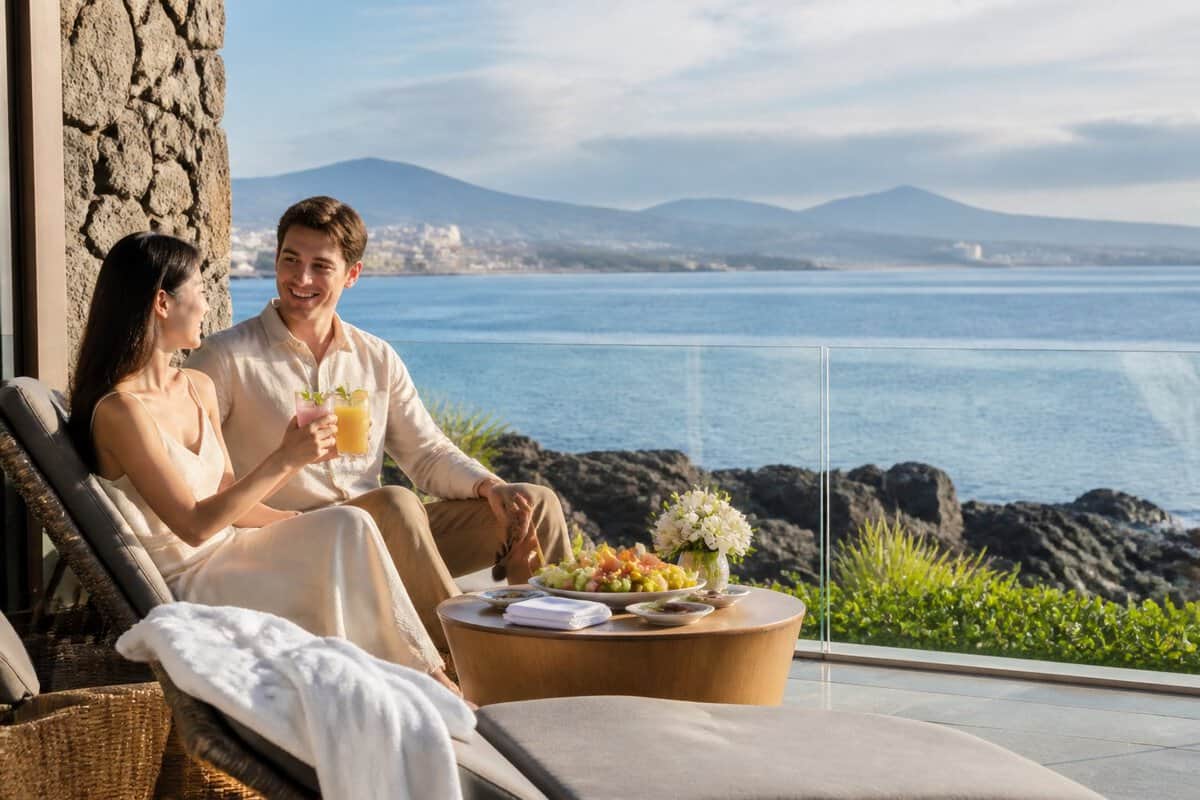 Newlywed couple relaxing on a luxury seaside resort terrace overlooking the South Korean coast.