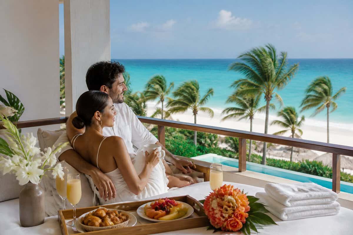 A newlywed couple enjoys breakfast on a luxury beachfront resort terrace overlooking the Caribbean Sea in Mexico.