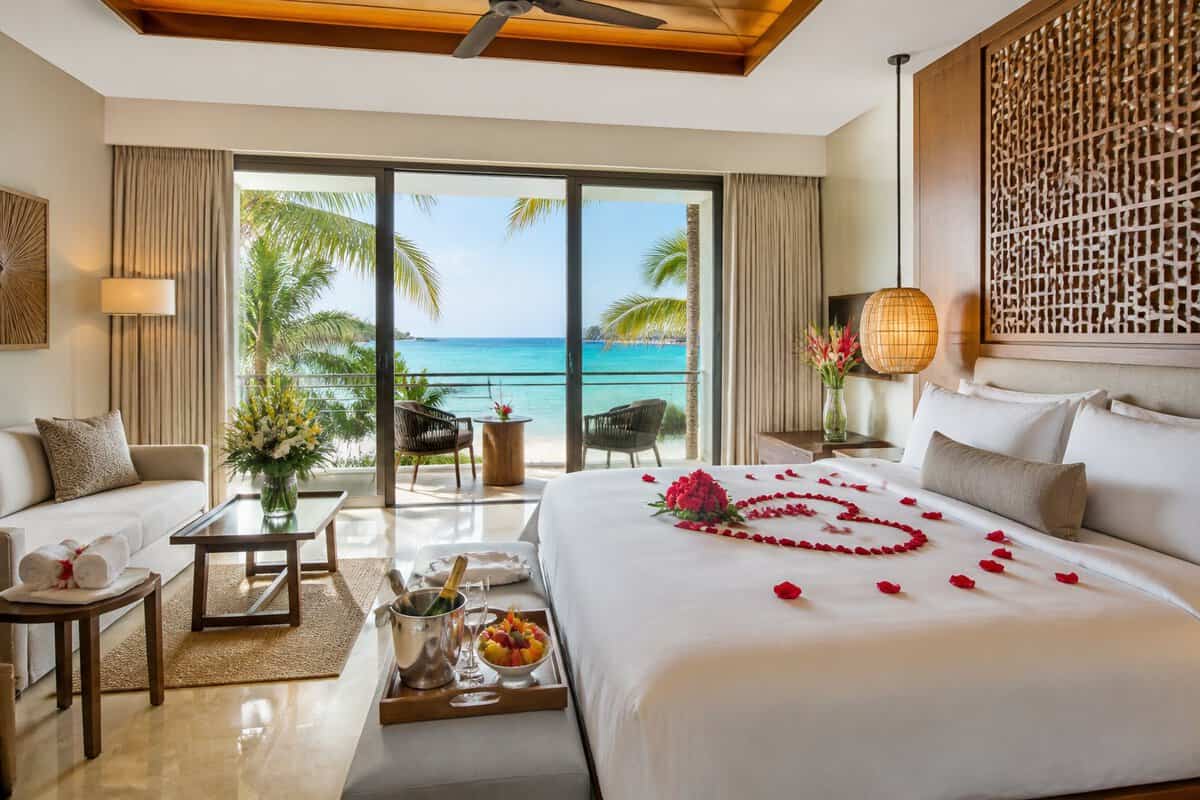 A luxurious honeymoon suite with a king-size bed, private balcony, and tropical ocean view.