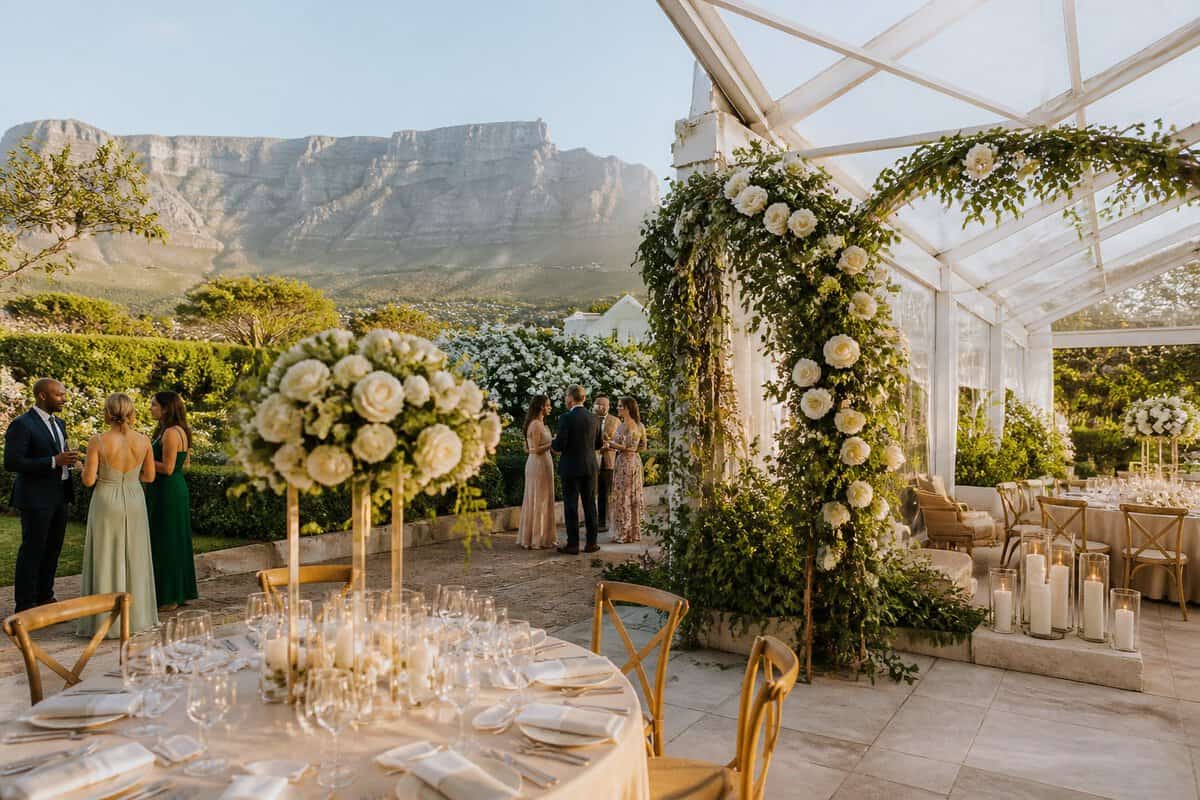 An elegant outdoor wedding reception at a Cape Town vineyard venue with mountains in the background.