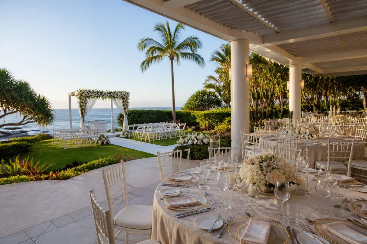 Elegant wedding venue with a flower-decorated ceremony arbor, outdoor dining area, tropical gardens, and ocean views.