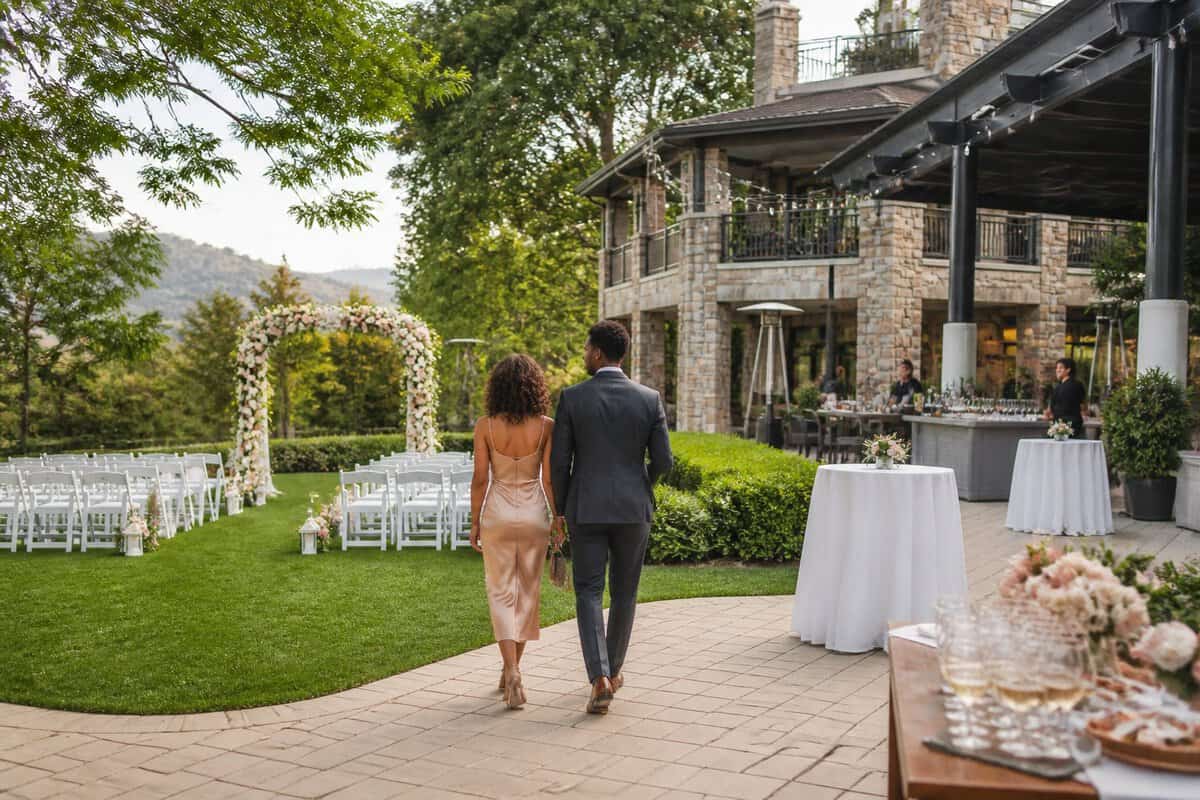 A couple explores an elegant all-inclusive wedding venue with a decorated outdoor ceremony area and landscaped grounds.