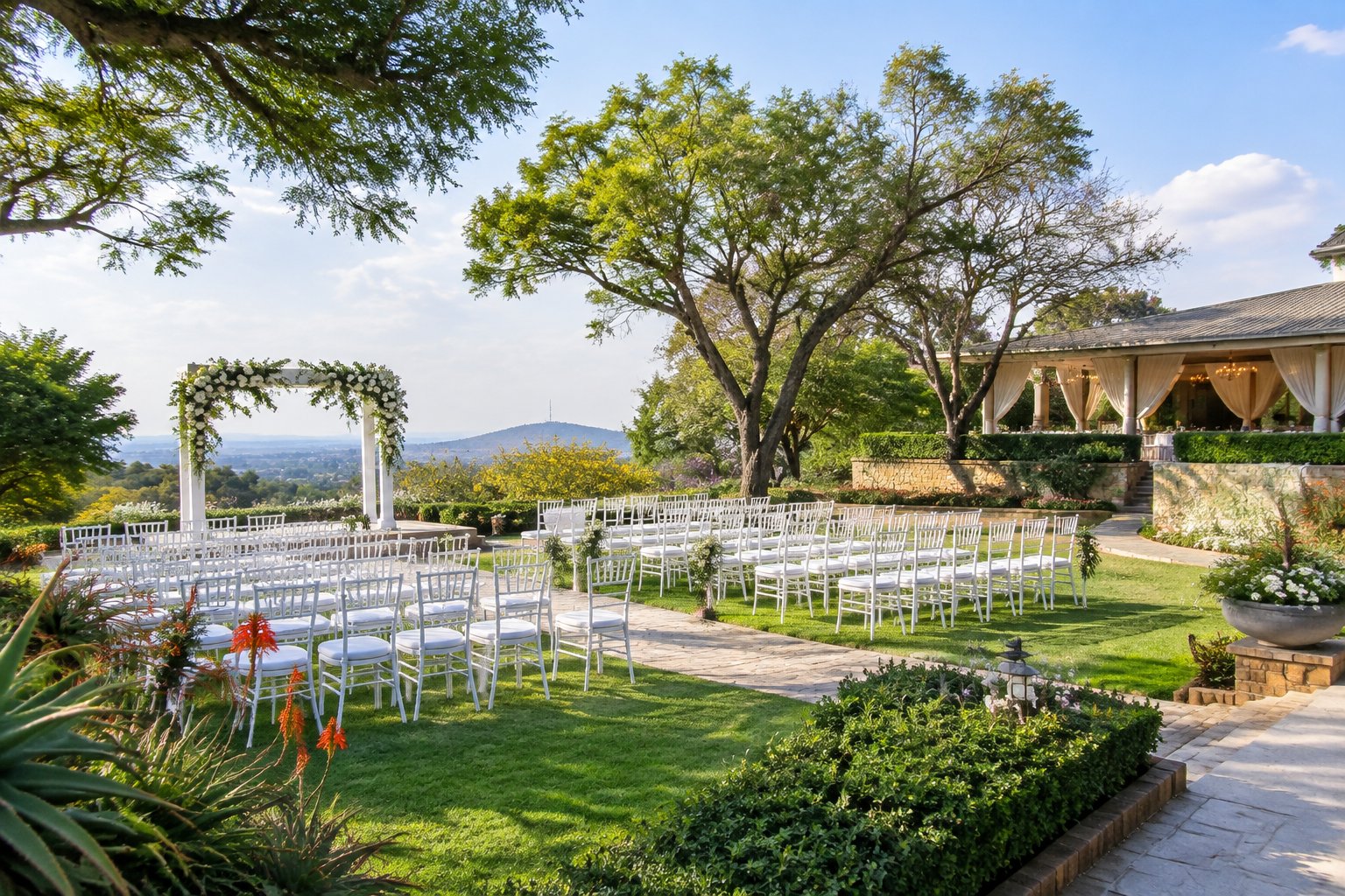 A landscaped garden wedding venue with white ceremony chairs, a floral arbor, green lawns, and flowering plants.