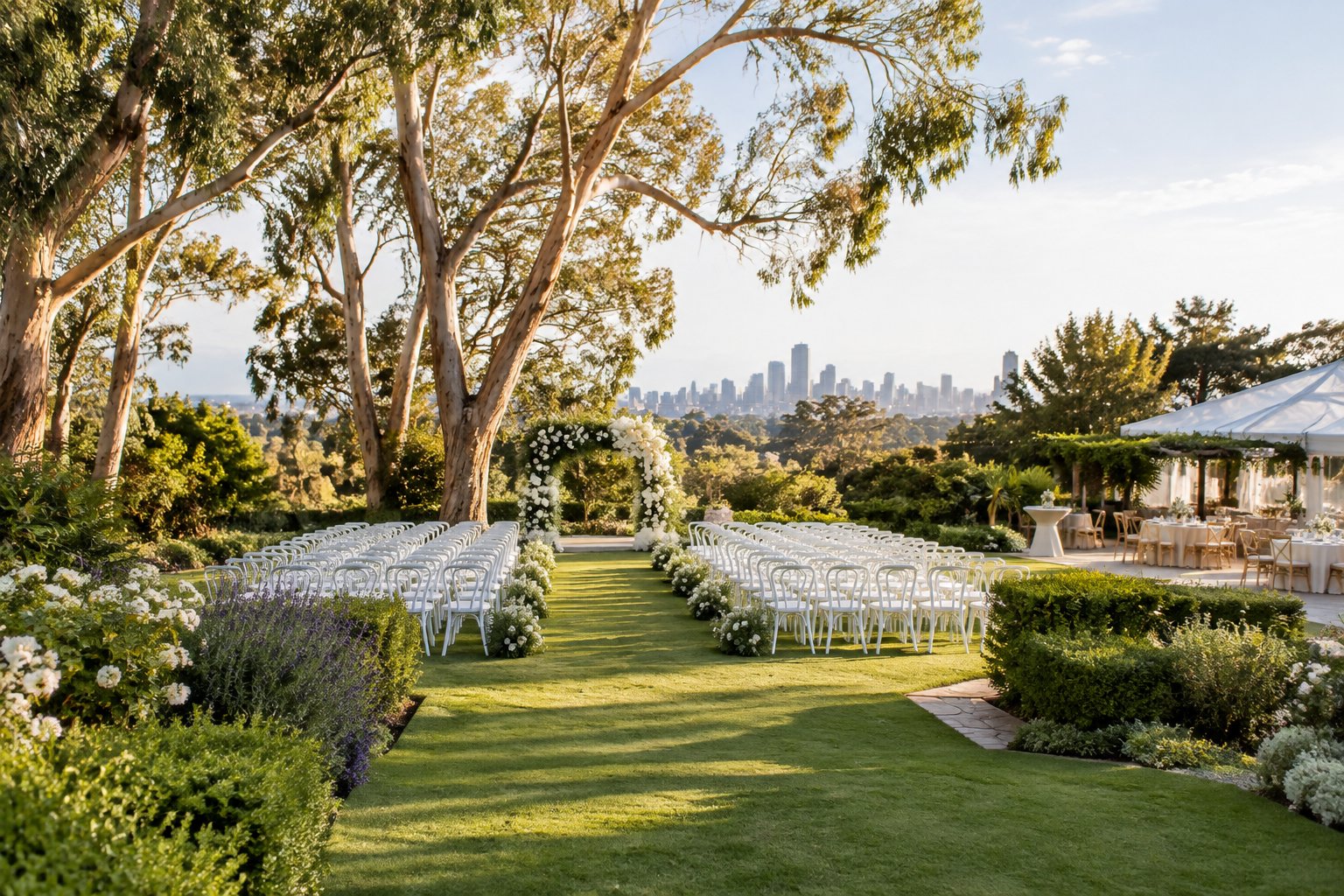 An elegant outdoor wedding ceremony set in a lush landscaped garden with white chairs and a floral arbor.