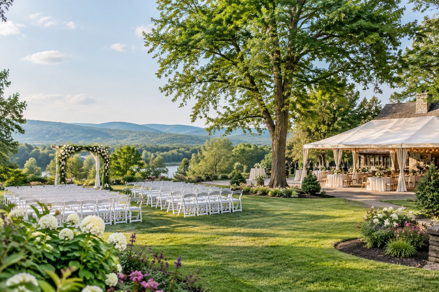 An elegant outdoor wedding venue with white chairs, a floral arbor, gardens, lawns, and Vermont countryside views.