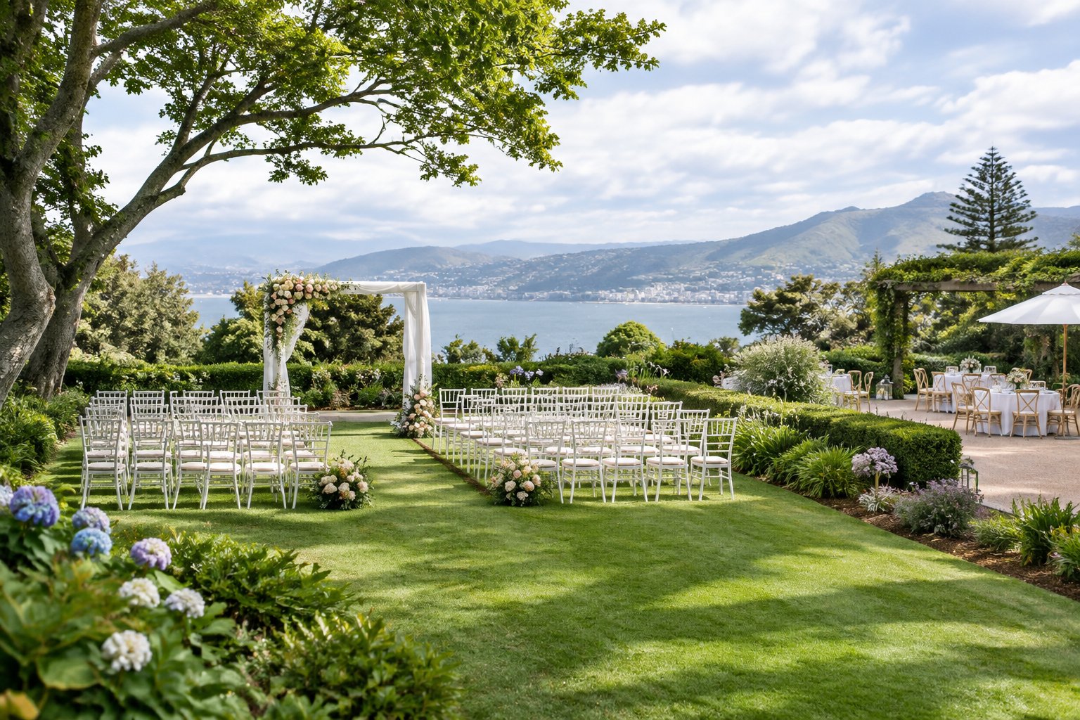 Elegant garden wedding venue with a flower-decorated arbor, white chairs, manicured lawns, and distant hills.