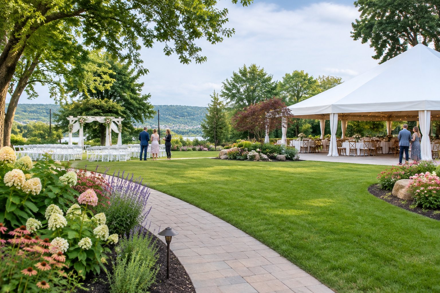 A landscaped garden wedding venue with a ceremony arbor, reception area, tables, flowers, and people viewing the grounds.