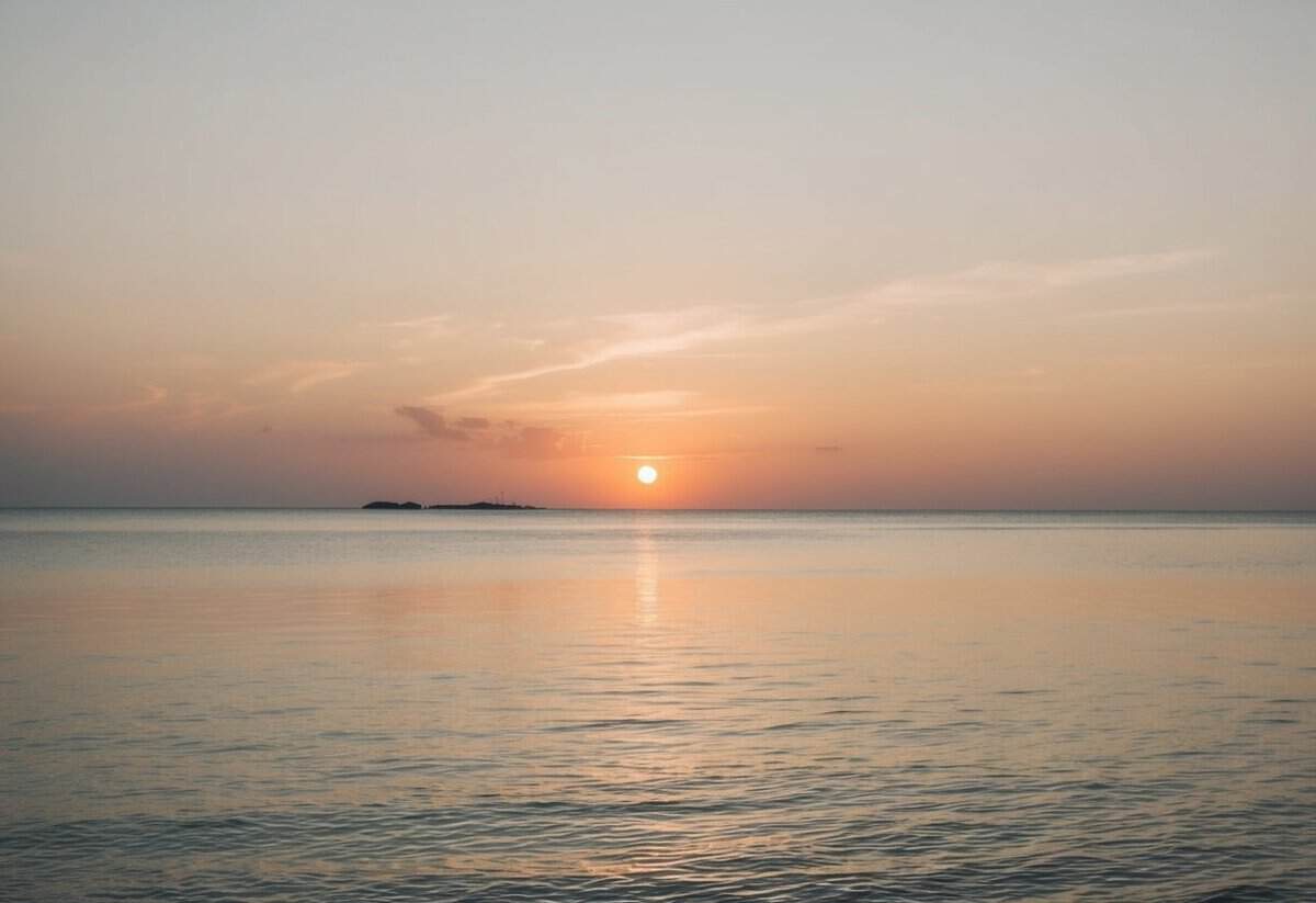 A serene sunset over a tranquil beach, with a softly glowing sky and calm waters, creating a peaceful and romantic atmosphere for a wedding ceremony