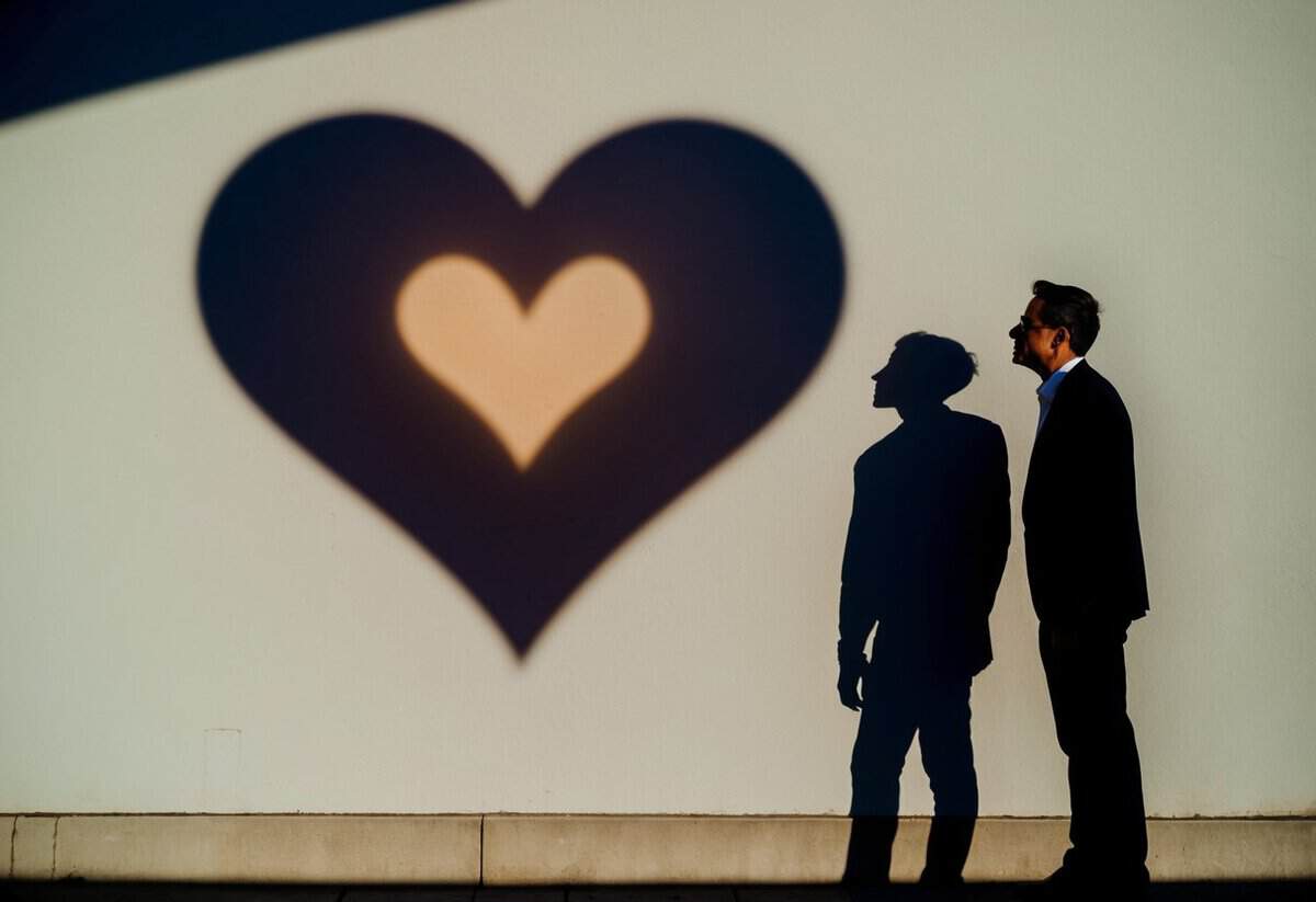 A man's heart-shaped shadow cast on a wall, with a trembling silhouette standing beside it