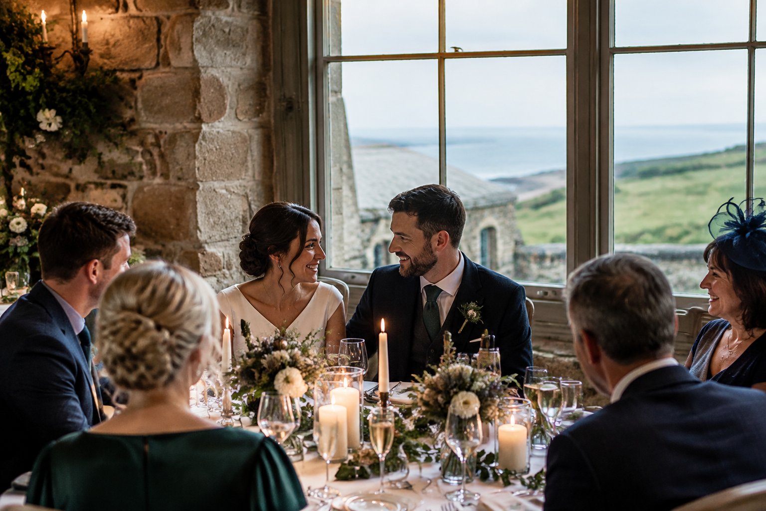 A couple celebrates with a small group of guests in a stone wedding venue overlooking the coast.