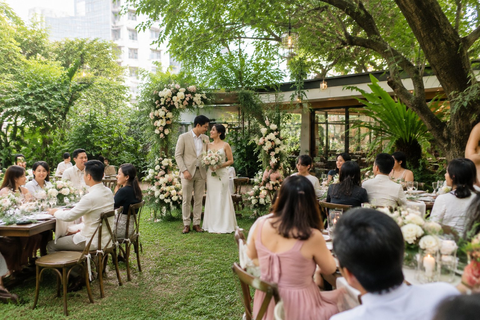 A couple celebrates with guests at a small garden wedding reception.