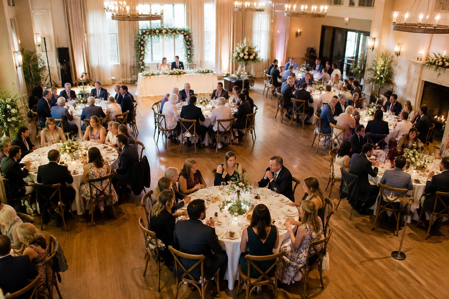 Wedding guests seated at tables in a reception venue.