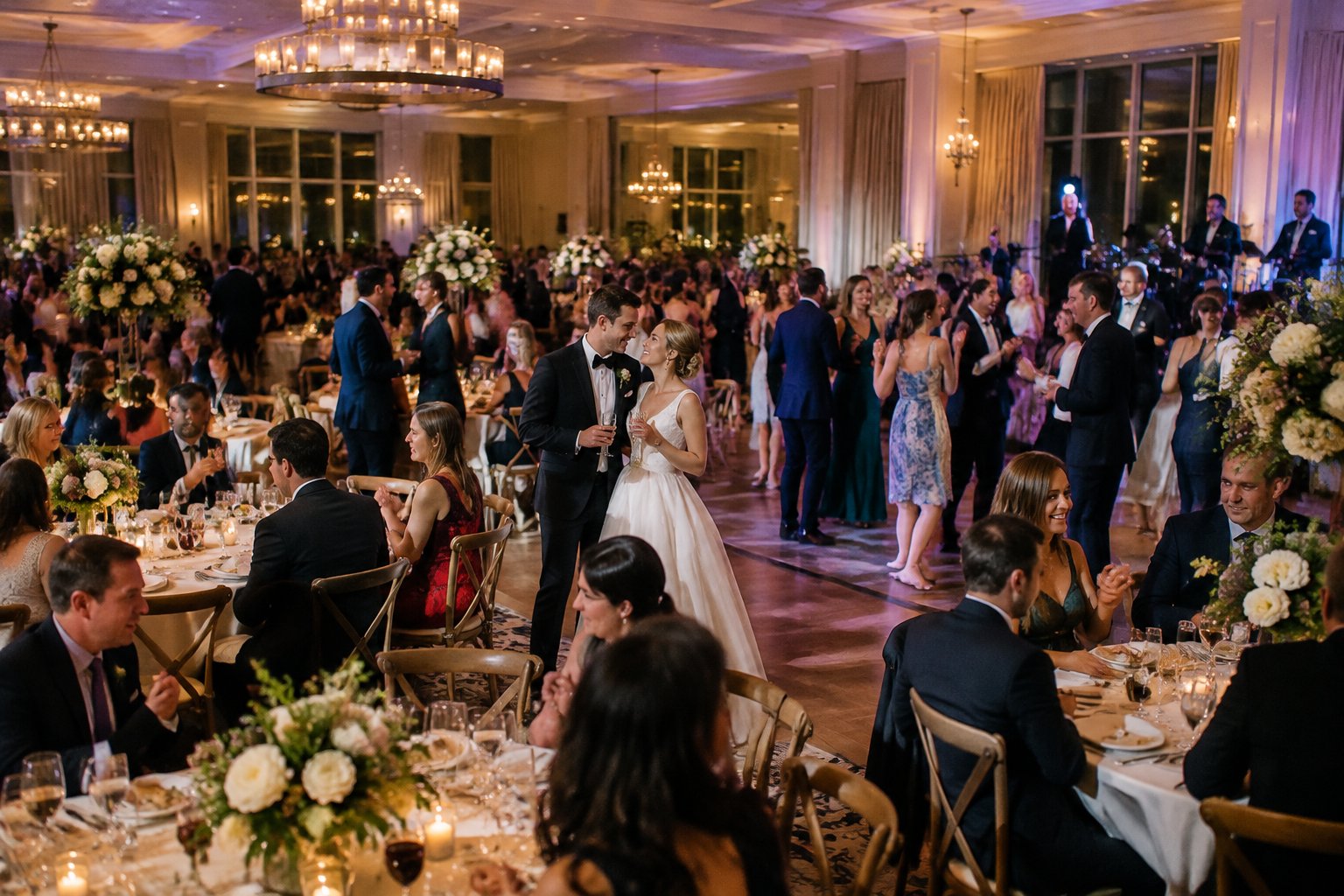 A newlywed couple celebrates with guests at a large wedding reception.