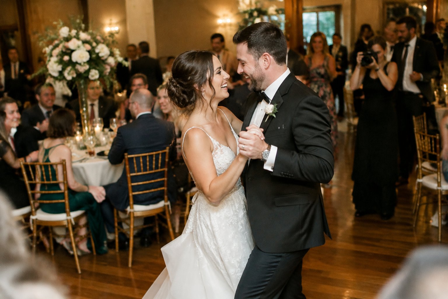 A newly married couple dances as guests celebrate at their wedding reception.
