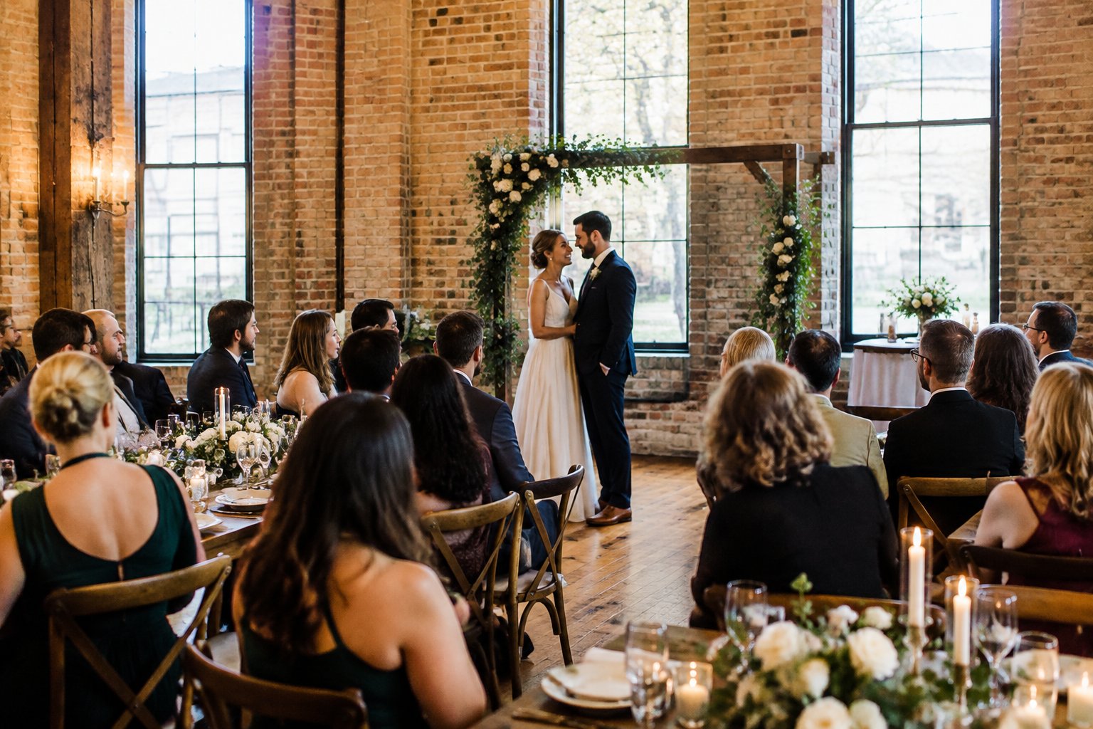 A couple shares a joyful moment at a small wedding gathering in a warmly decorated venue.