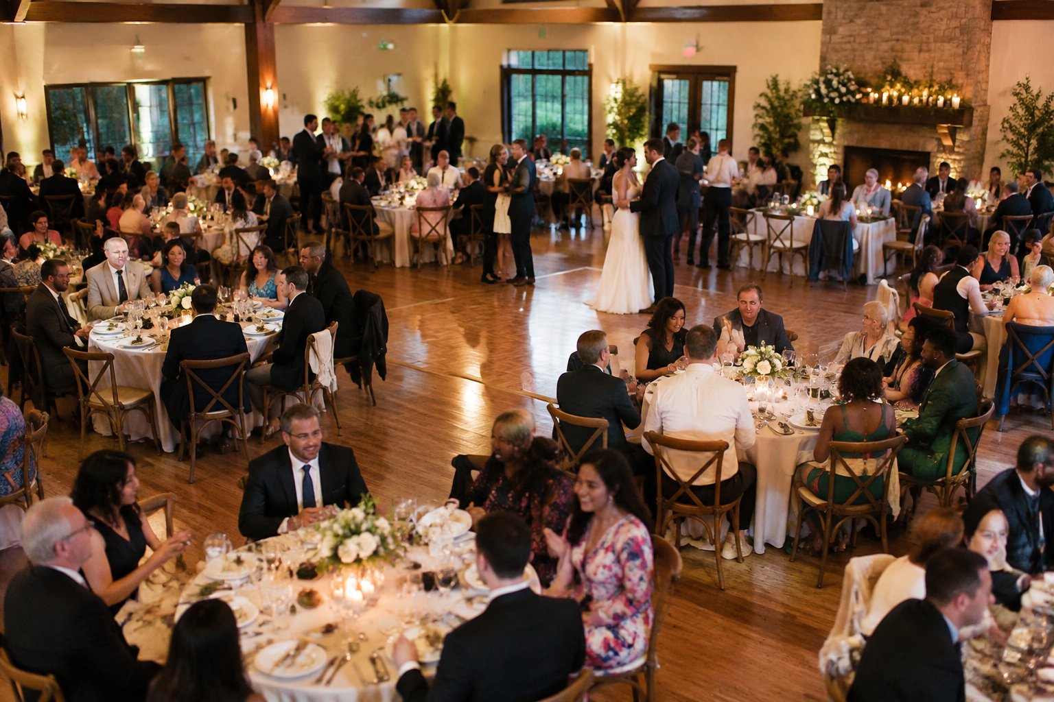 Wedding guests gather at decorated tables during a reception.
