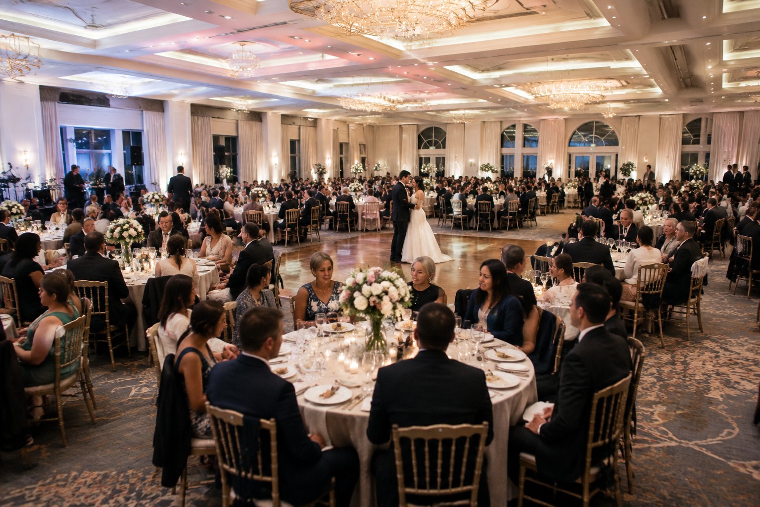 A newlywed couple celebrates with a large gathering of guests at a wedding reception.
