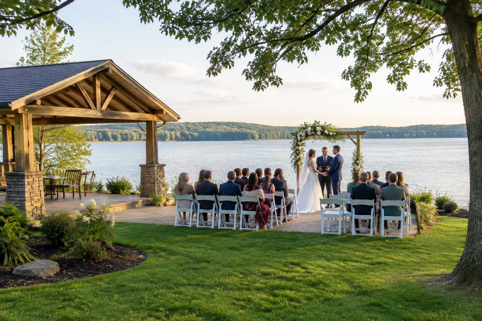 A wedding ceremony set beside a lake, with guests seated on a grassy lawn.